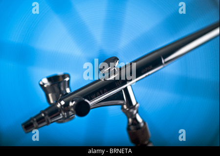 Iwata-Airbrush mit Seite Tasse auf einem kühlen blauen Hintergrund. Stockfoto