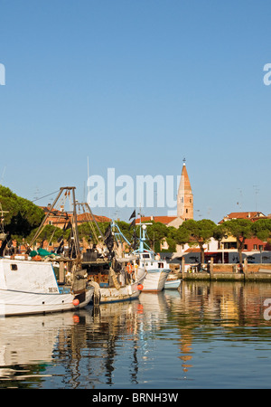 Fischerboote und Yachten auf dem Wasser Kanal mit Dom Glockenturm (Campanile) im Hintergrund, Caorle, Venetien, Italien Stockfoto