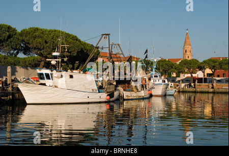 Fischerboote und Yachten auf dem Wasser Kanal mit Dom Glockenturm (Campanile) im Hintergrund, Caorle, Venetien, Italien Stockfoto