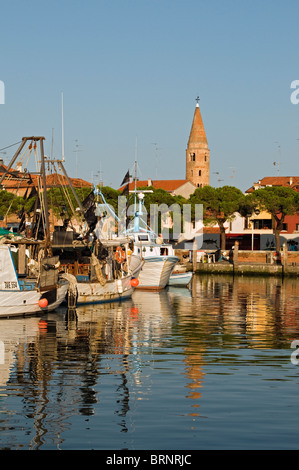 Fischerboote und Yachten auf dem Wasser Kanal mit Dom Glockenturm (Campanile) im Hintergrund, Caorle, Venetien, Italien Stockfoto