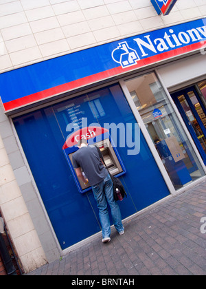 Ein junger Mann entzieht ein Nationwide Building Society ATM oder Geldautomat Bargeld Stockfoto