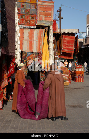 MARRAKESCH: ZWEI MUSLIMISCHE MÄNNER TRAGEN TEPPICH IM SOUK Stockfoto