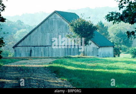 Ländliche Hang hölzerne Scheune sitzt auf grüner Wiese hoch zwischen sanften Hügeln im Frühsommer, in Missouri Stockfoto