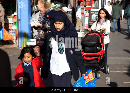 Menschen aus verschiedenen ethnischen, überwiegend muslimischen Hintergründe rund um den Markt auf Whitechapel High Street in East London. Stockfoto