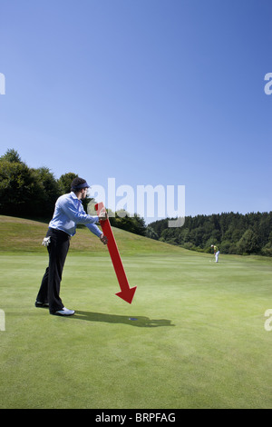 Caddy zeigt auf ein Loch am Golfplatz Stockfoto