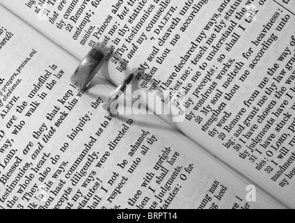 Trauringe erstellen ein Herz Formen Schatten auf eine Bibel Stockfoto