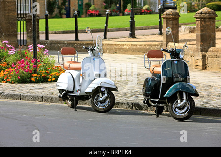 Eine Lambretta und Vespa Roller geparkt am Straßenrand in England Stockfoto