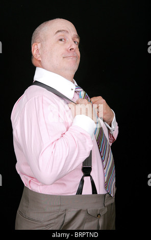 ein Mann mittleren Alters in einem rosa Hemd auf schwarzem Hintergrund Stockfoto