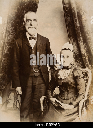 Älteres Ehepaar viktorianischen Ehemann und Ehefrau posieren in einem Fotografen Studio um 1880 Stockfoto