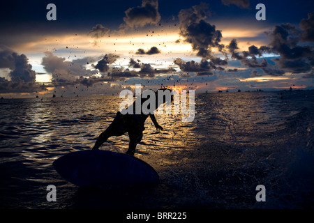 Eine überfliegen Boarder schnitzt durch eine brechende Welle bei Sonnenuntergang am Long Beach auf Boracay, Philippinen. Stockfoto