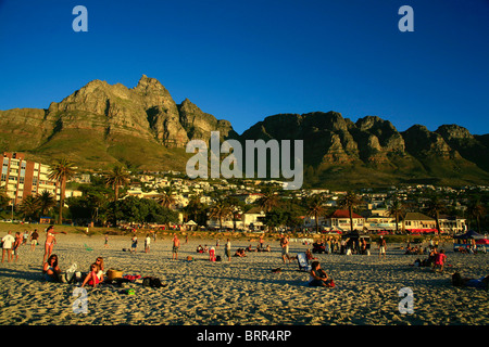Menschen entspannen am Strand von Camps Bay, Tafelberg und zwölf Apostel im Hintergrund Stockfoto