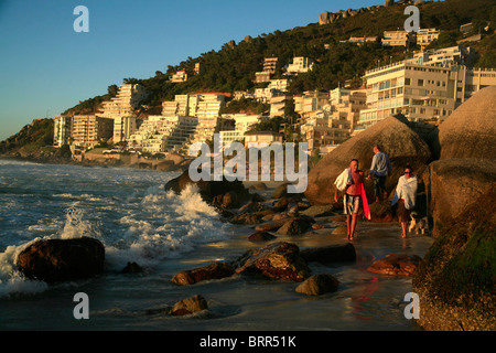 Menschen zu Fuß auf Clifton Beach bei Sonnenuntergang mit Luxusapartments direkt am Meer hinter Ihnen Stockfoto