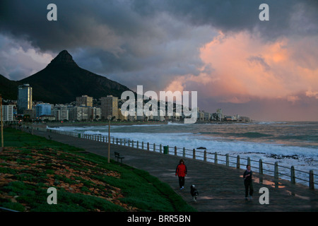 Sea Point Promenade mit stürmischen Wolken über dem Atlantischen Ozean und Lion es Head im Hintergrund Stockfoto