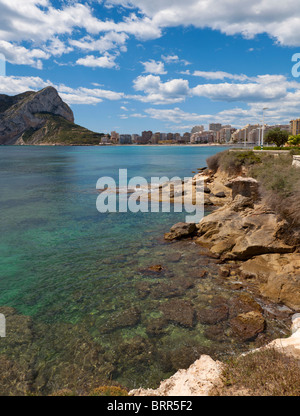 Playa La Fosa, Calpe, mit Felsen und verführerisch transparentes Wasser, Strand und im Hintergrund die riesigen Felsen von Ifach (324 m) Stockfoto