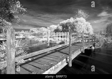 Infra Rot Holzbrücke über den Fluss Test dunklen Himmel weiße Blätter schwarz / weiß Stockfoto