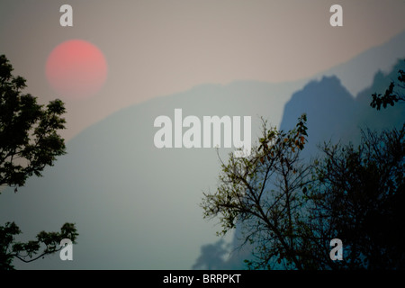 Untergehende Sonne durch die dichte Atmosphäre mitten in den Bergen von Laos. Stockfoto