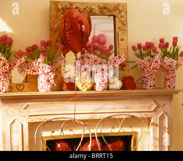 Nahaufnahme von roten Tulpen in gefleckte Papier auf Kaminsims in Valentine Dining Themenzimmer eingewickelt Stockfoto