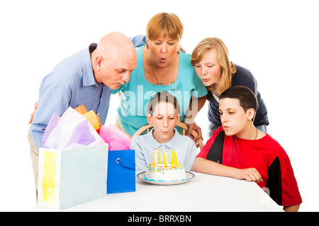 Familie hilft einen wenig junge Schlag die Geburtstagskerzen auf seinen Kuchen. Isoliert auf weiss. Stockfoto