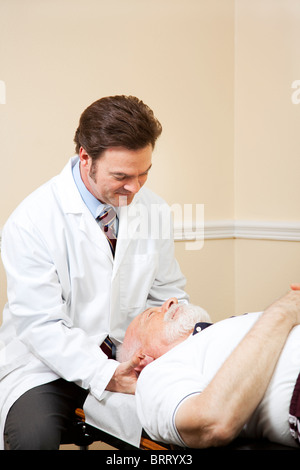 Chiropraktiker passt an den Hals eines älteren männlichen Patienten. Stockfoto