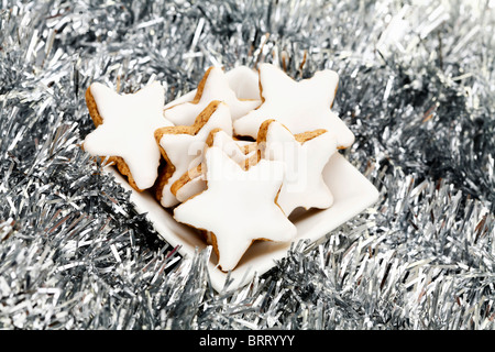 Sternförmige Zimt Cookies in einer Schüssel mit Weihnachtsschmuck Stockfoto