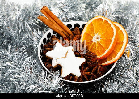 Sternförmige Zimt Kekse mit getrockneten Scheiben Orange, Zimtstangen und Anis Sterne in einer Schüssel mit Weihnachtsschmuck Stockfoto