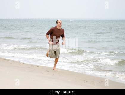 ein junger passen Mann läuft am Strand entlang Stockfoto