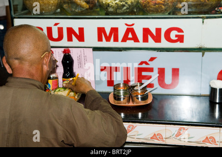Ein alte vietnamesischer Mann genießt seine traditionelle Suppe Nudelgericht bekannt als Pho in einem kleinen Restaurant in Saigon Ben Thanh Market. Stockfoto