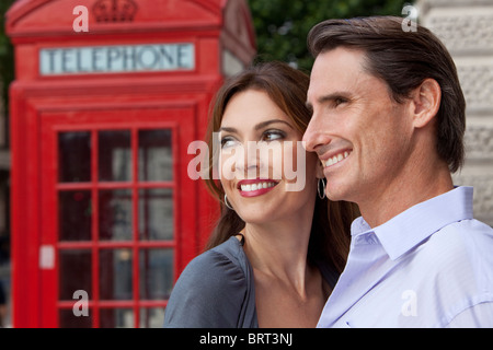 Ein romantisches glücklich Mann und Frau Paar in London, England, mit einer klassischen roten Telefonzelle unscharf hinter ihm Stockfoto