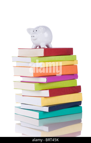 Piggy Bank über einen Stapel bunten Bücher (isoliert auf weiss) Stockfoto