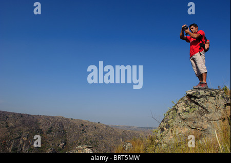 Mann mit rotem T-shirt auf einem Berg vor einem blauen Himmel in Saia Brava Naturschutzgebiet, Vale Côa, Portugal Stockfoto