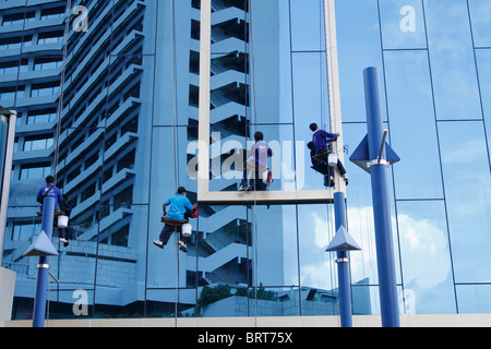 Fensterputzer (Scheibenwischer) Reinigung (Arbeits-) gehängt auf ein Hochhaus Gebäude Fassade (Wolkenkratzer) Bangkok, Thailand, August 2010 Stockfoto