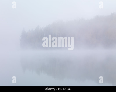 Fallen Sie am frühen Morgen Naturkulisse der Nebel steigt über die Pfeilspitze See enthüllt herbstlichen Wald hinter. Ontario, Kanada. Stockfoto