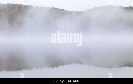 Fallen Sie am frühen Morgen Naturkulisse der Nebel steigt über die Pfeilspitze See enthüllt herbstlichen Wald hinter. Ontario, Kanada. Stockfoto