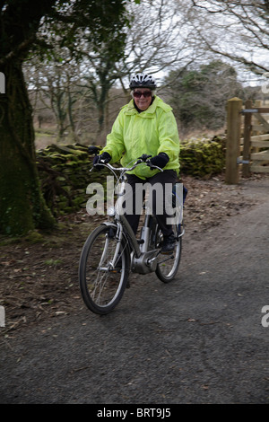 Ältere ältere Dame Reiten Riese elektrisch unterstützt e-Bike auf Sustrans Route 27 Radweg in der Nähe von Yelverton Devon UK Stockfoto