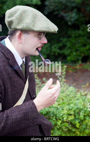 Mustached Mann in flache Kappe mit Brille Rauchen Geradschaft Tabak Pfeife der 1940er Jahre Kleidung Stockfoto
