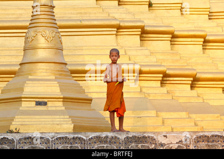 Ein junger Thai Mönch steht auf der Basis eines Stupa Stockfoto