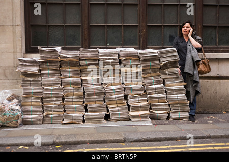 Stapel von Evening Standard Zeitungen werden in einer Seitenstraße in der Nähe von Holborn Station als Pendler macht Handy-Anruf gestapelt. Stockfoto