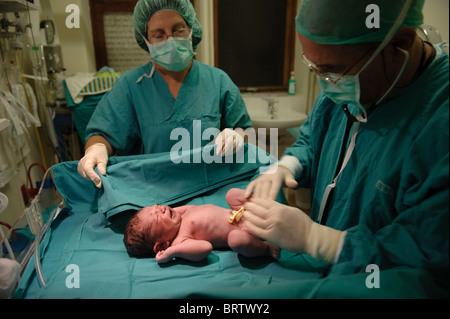 Neugeborenes Baby wird durch eine Krankenschwester und ein Arzt nach einer Kaiserschnitt Geburt untersucht. Stockfoto