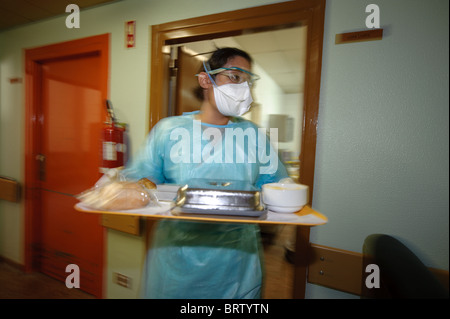 Gesundheitsfachkraft mit Schutzmaske trägt ein Tablett mit Mahlzeiten für die Patienten in einem Krankenhaus - Corona-Virus des Coronavirus Coronas Stockfoto