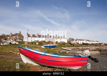 Rotes Boot an der Küste am Hafen in einem kleinen Fischerdorf an der nordöstlichen Küste Northumbrias. Craster, Northumberland, England, Großbritannien. Stockfoto