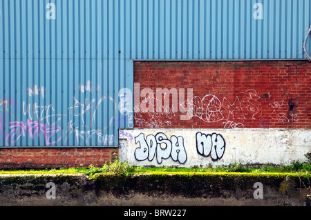 Blue metal and red brick wall  with graffiti Stockfoto