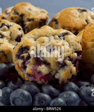 kleine Stapel von Blaubeer-Muffins und frische Heidelbeeren über einen blauen Hintergrund closeup Stockfoto