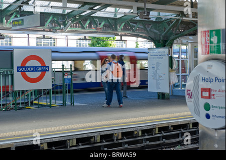 Golders Green über dem Boden U-Bahn Station Passagiere Bahnsteig Junge mit orangefarbenem Rucksack & Mädchen in Sonnenbrille wartet auf U-Bahn-Schild Schilder Stockfoto