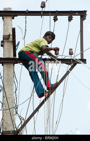Indische Elektriker arbeiten bis ein Strommast in den Straßen von Puttaparthi, Andhra Pradesh, Indien Stockfoto