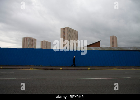 Mann zu Fuß vorbei an Wand vor der großen Gehäuse Hochhäusern n Glasgow Schottland Stockfoto