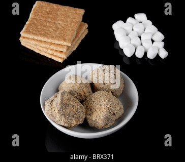 Zutaten für s' mores Trüffel Candy auf einer schwarzen Platte einschließlich Graham Cracker, Schokoladenstückchen und Mini marshmallows Stockfoto