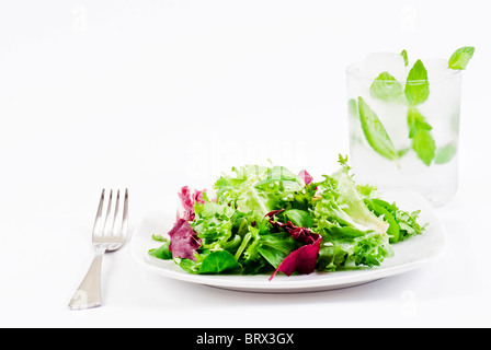 Mischung aus knackig und süß Salat Blätter mit Glas eiskaltes Wasser mit Minze Stockfoto