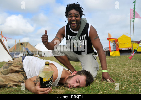 Mann liegt auf dem Rasen mit Flasche Cidre, Freund lachen Stockfoto