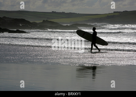 Surfer in der Abenddämmerung auf Polzeath Strand, Cornwall, England, UK. Stockfoto