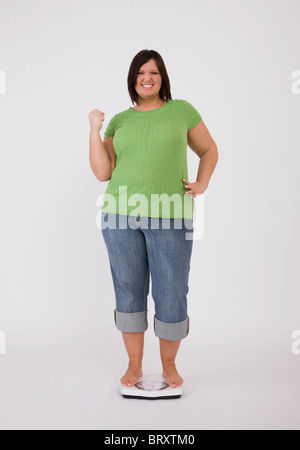 Portrait von junge übergewichtige Frau stehend auf Skalen und jubeln Stockfoto